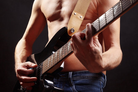 Rock guitarist playing solo on guitar on a dark stage.の写真素材