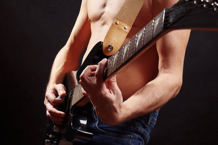 Artist playing chord on guitar on a dark stage.の写真素材