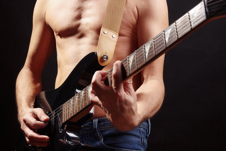 Musician playing chord on guitar on a dark stage.の写真素材