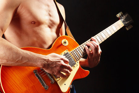 Musician plays the orange electric guitar on a dark stage.の写真素材