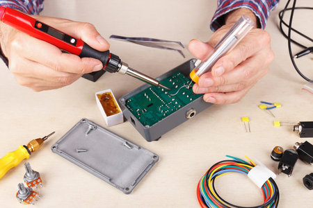 Electronics engineer solder electrical hardware at the service workplace.