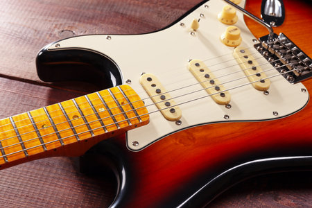 Sunburst guitar closeup on the wooden background. Selective focus.