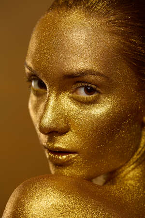 Close up portrait beautiful woman golden skin sparkles glitter studioの写真素材