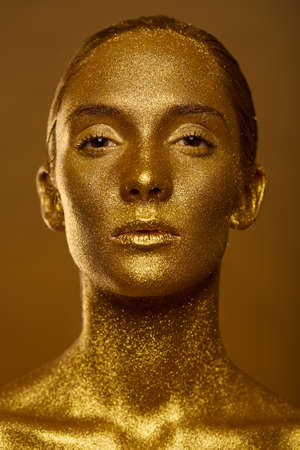 Close up portrait beautiful woman golden skin sparkles glitter studioの写真素材