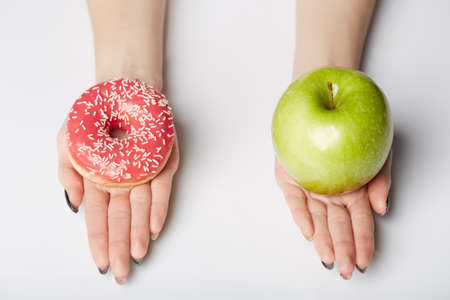 hands hold donut and apple on white backgroundの写真素材
