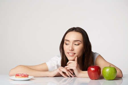 woman beauty girl with fruits and donut apple on gray white backgroundの写真素材