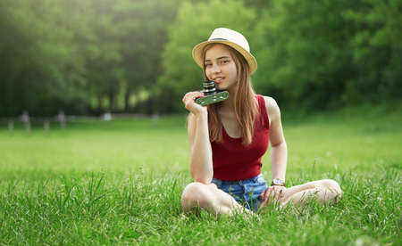 cute girl with camera on grass summerの写真素材