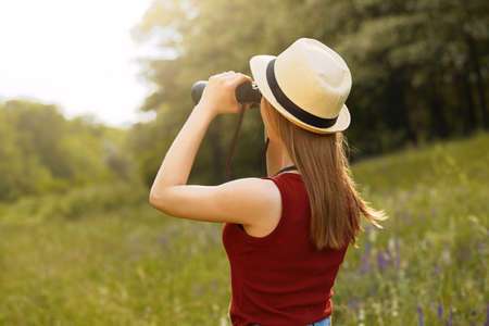 Young girl on nature with hat and binocular. Summerの写真素材