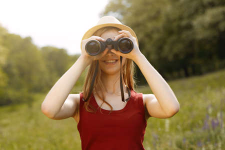 Young girl on nature with hat and binocular. Summerの写真素材
