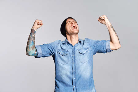 Handsome man is yelling and enjoy success on white wall at studioの写真素材