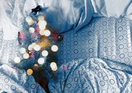 Decorated bright classic Christmas tree lying in blue bed in the morning. Concept of a home holiday...