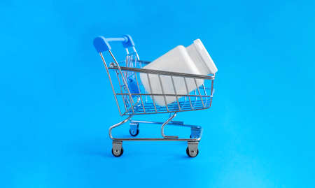 Shopping basket and medical jar with pills for the treatment of colds, flu, and viral diseases. Medical concept of purchasing medical drugs, medications or cosmetics on blue background.の写真素材