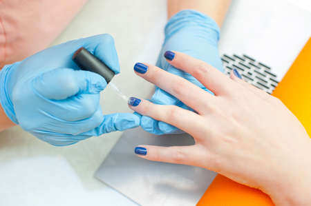 Beautician making manicure in spa or beauty salon - painting fingernails の写真素材