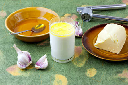 home made remedy for flu  glass of hot milk with honey, butter and garlicの写真素材