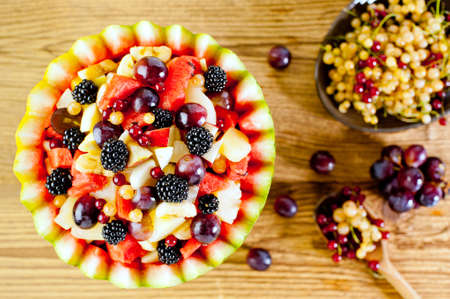 Fresh fruit summer salad in watermelon bowl at wooden backgroundの写真素材