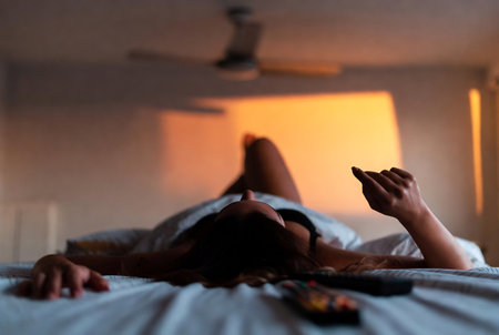 Young woman lying on the bed and using mobile phone in the bedroomの素材