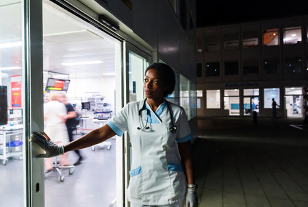 Young african american female doctor in hospital corridor at night.の素材