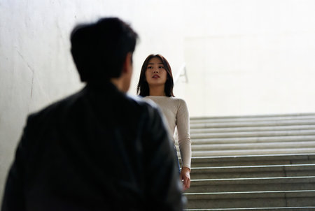 Young Asian couple walking down the stairs in the city. They are looking at each other.の素材