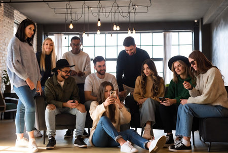 Group of young people sitting on the floor and using their smartphones.の素材