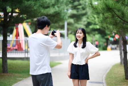 Young asian couple taking a photo of themselves in the park.の素材