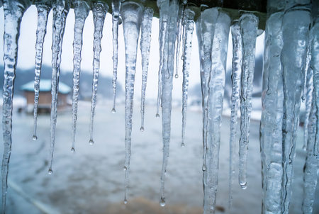 Icicles hanging from the roof of a house in winter.の素材
