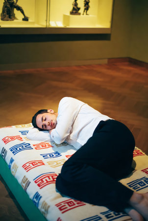 Young man is lying on a stretcher in an art gallery.の素材