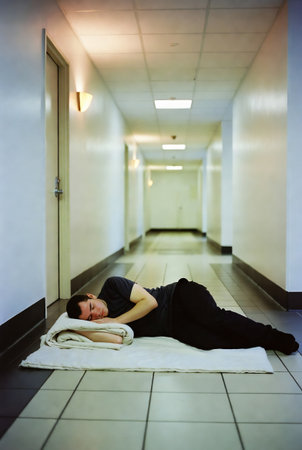 Young woman lying on the floor with eyes closed in hospital corridor.の素材