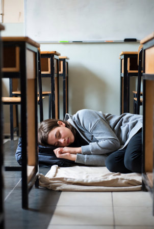 Young woman sleeping on the floor in the classroom at the elementary schoolの素材