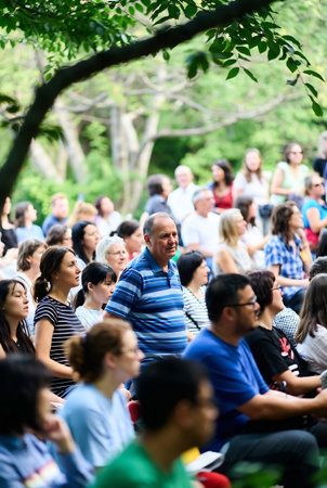 People sit and listen to the music in a public park on a summer dayの素材