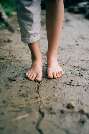 little boy walking barefoot on the ground in the summer, shallow depth of fieldの素材