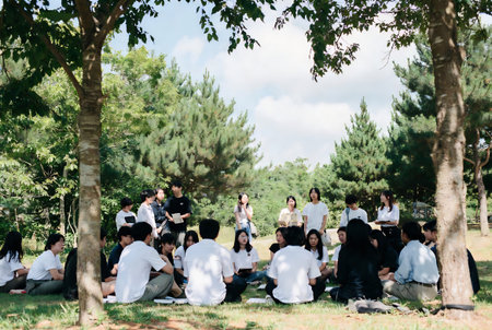 Group of students sitting in the park and listening to the teacher.の素材