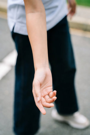 Young woman holding her hand outstretched in the park. Close up.の素材