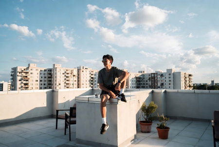 Young man in sportswear sitting on the roof of a buildingの素材