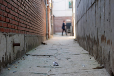 Brick wall and a man walking on the street in the cityの素材