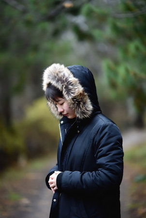 Portrait of a young woman in a winter jacket in the forestの素材