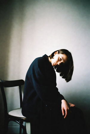 Portrait of a beautiful young woman in a black coat sitting on a chairの素材