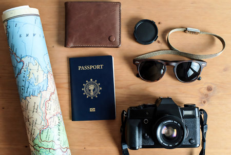 Tourist essentials on wooden background. Passport, camera, map and sunglassesの素材