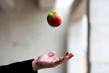 Close up of a person throwing an apple into the air with blurred backgroundの素材