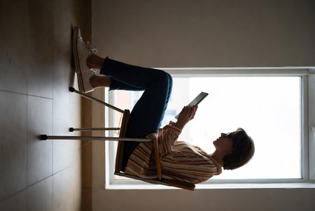 Young woman sitting on a chair and reading a book. Back viewの素材