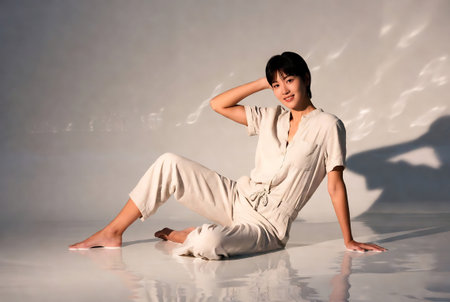 Beautiful Asian woman in white suit sitting on the floor, studio shotの素材