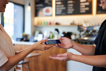 Coffee shop staff using mobile phone at counter in coffee shopの素材
