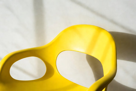 Yellow plastic chair with shadow on the wall. Close-up.の素材