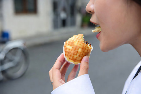 Woman eating a waffle in the street, closeup of photoの素材
