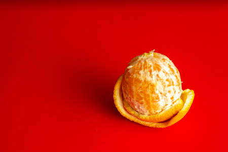 Peeled orange on a red background. Summer, tropical composition.の写真素材