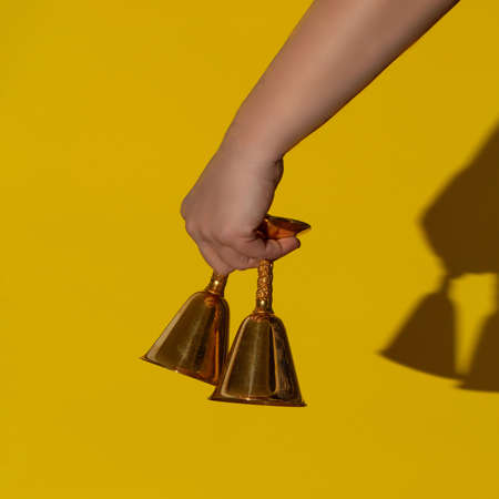 Golden glasses like a bell. A classic invitation to socialize. Minimal concept on pastel yellow...