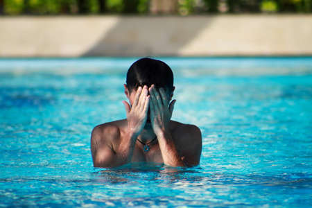 man touch face in blue waterの写真素材