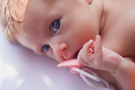 baby lie with toy and rattle and look in cameraの写真素材