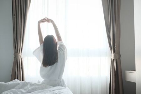 Woman stretching in bed after wake up, back viewの写真素材
