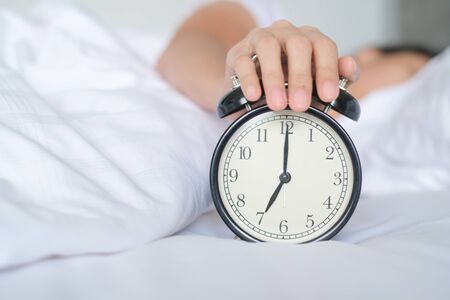 Woman sleep on the bed turns off the alarm clock wake up at the morning, Selective focus.
の写真素材