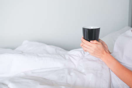 woman hold coffee cup on bed.の写真素材